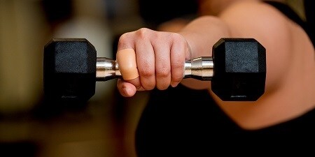 Esparadrapo Active Tape en el dedo de la persona que levanta una mancuerna
