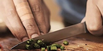 hombre cortando cebollinos en una tabla de cocina
