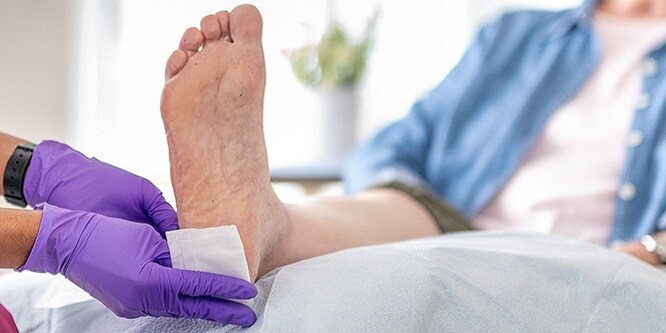 Una enfermera pone un apósito en el talón de un paciente
