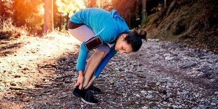 Mujer comprobando el tobillo mientras corre
