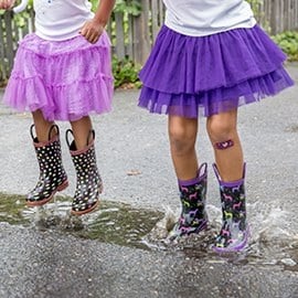 Dos niñas con tiras Nexcare jugando en un charco